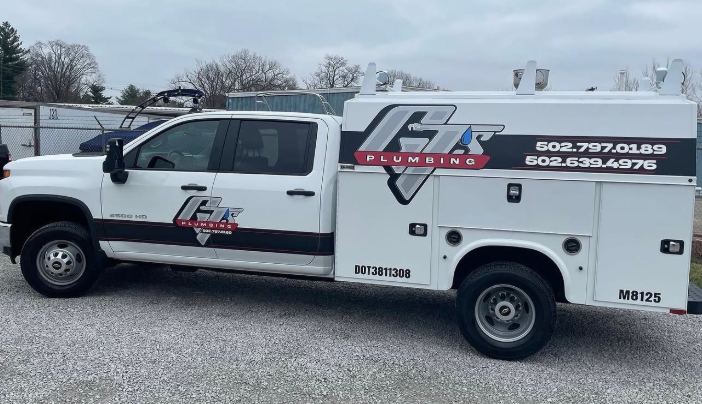 White utility truck with company logos and phone numbers parked on gravel lot