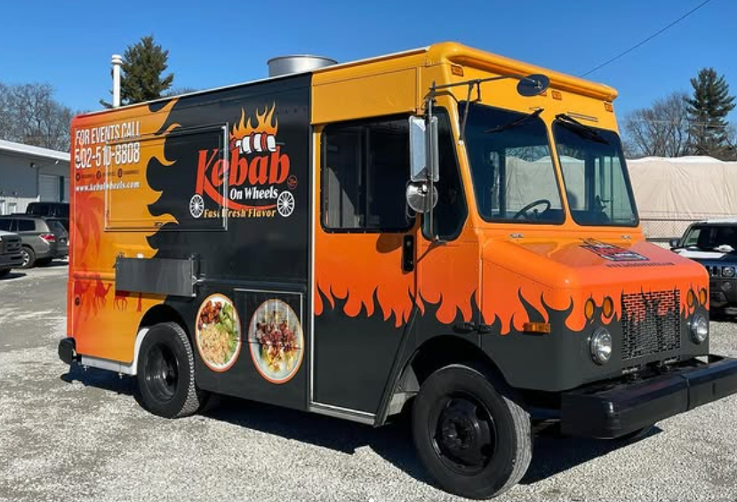 Orange-and-black kebab food truck parked outdoors on a sunny day