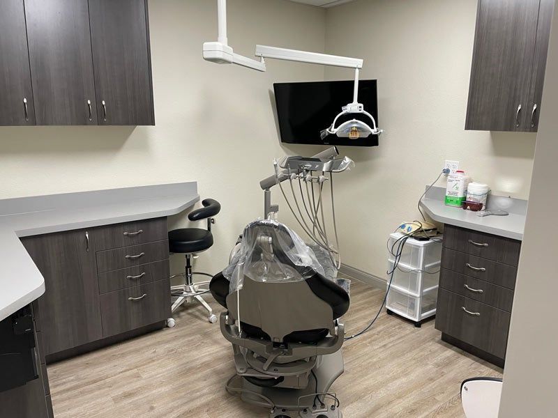 Dental operatory with chair, overhead light, monitor, and cabinets in a clean clinic room