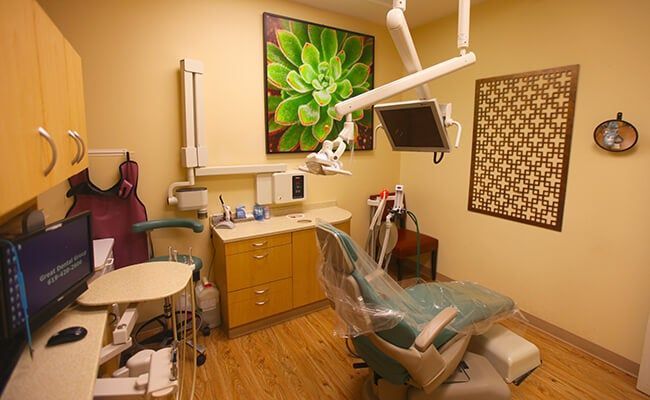 Dental exam room with chair, monitor, cabinets, and floral wall art