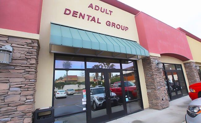 Adult Dental Group storefront with pink facade, green awning, and glass entrance.