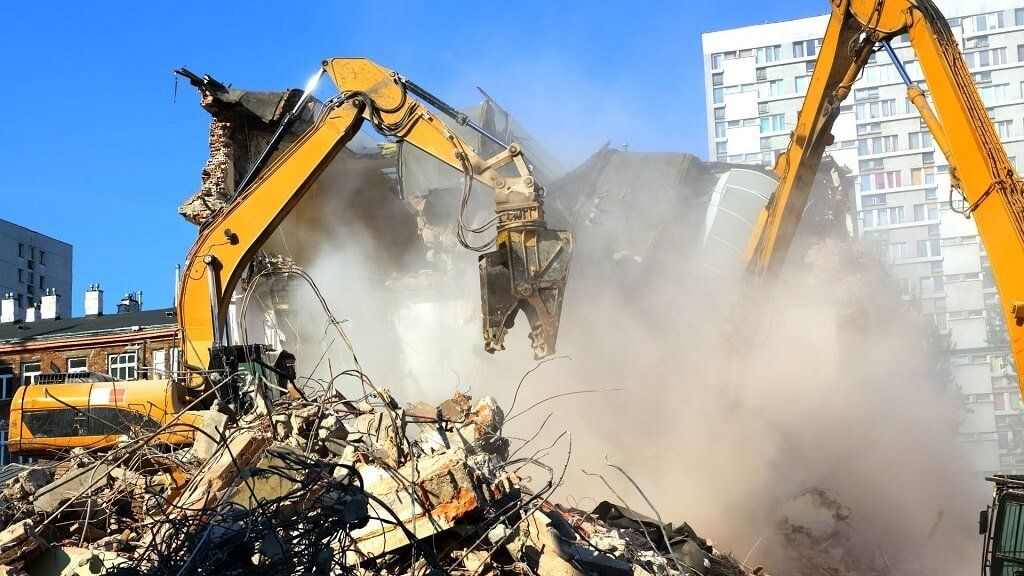 Two bulldozers are demolishing a building in a city