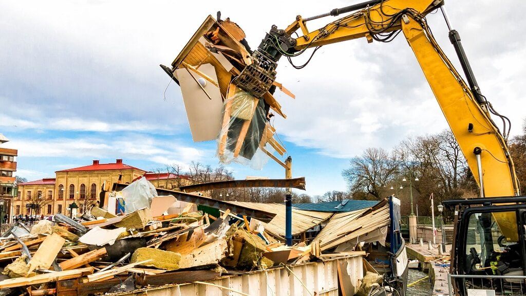 A yellow excavator is demolishing a building