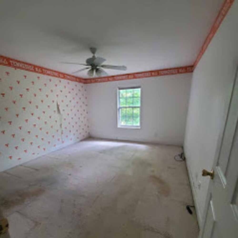 Empty bedroom with patterned wallpaper, white walls, a ceiling fan, and a single window.