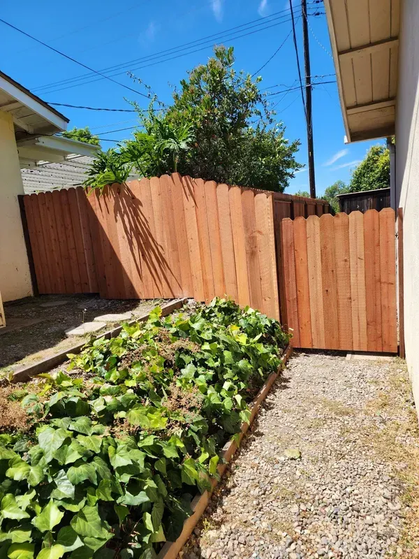 Wood fence and matching gate installed beside a residential home