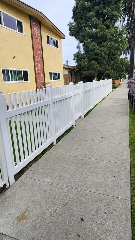 White vinyl picket fence lining a Los Angeles sidewalk