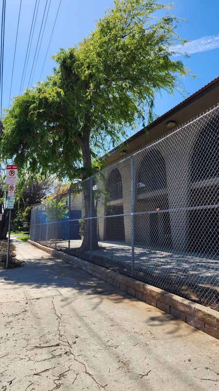 Chain-link fence with rolling gate and razor wire securing an industrial lot