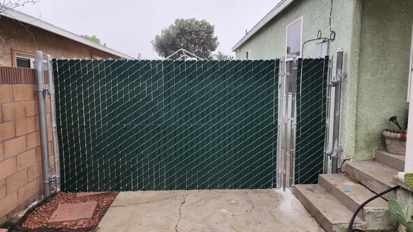 Green privacy slat chain-link gate installed in a residential backyard