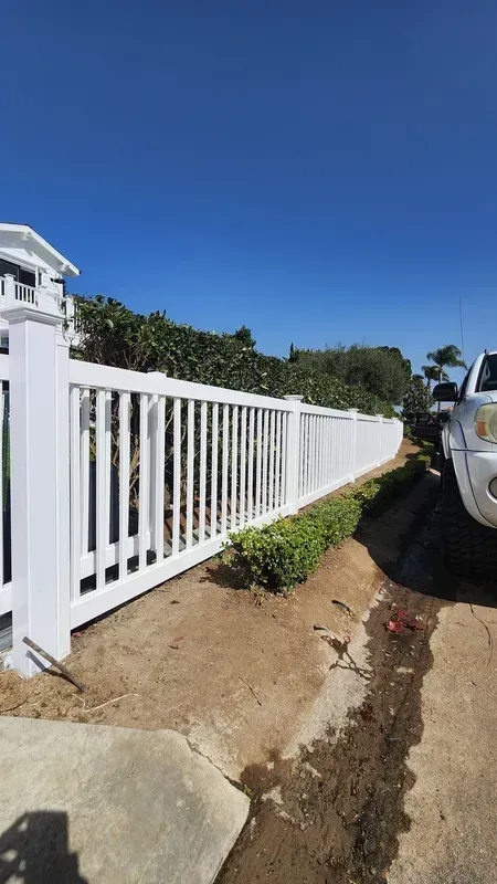 White vinyl picket fence bordering a residential driveway