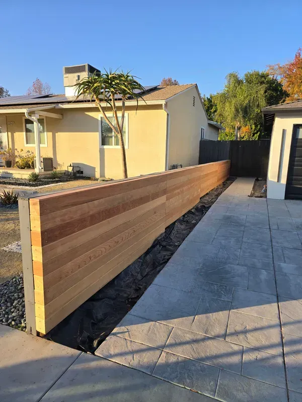Horizontal slat wood fence lining a Los Angeles driveway