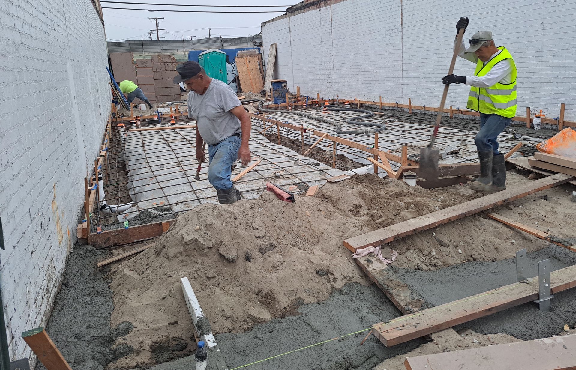 A group of construction workers are working on a concrete floor.