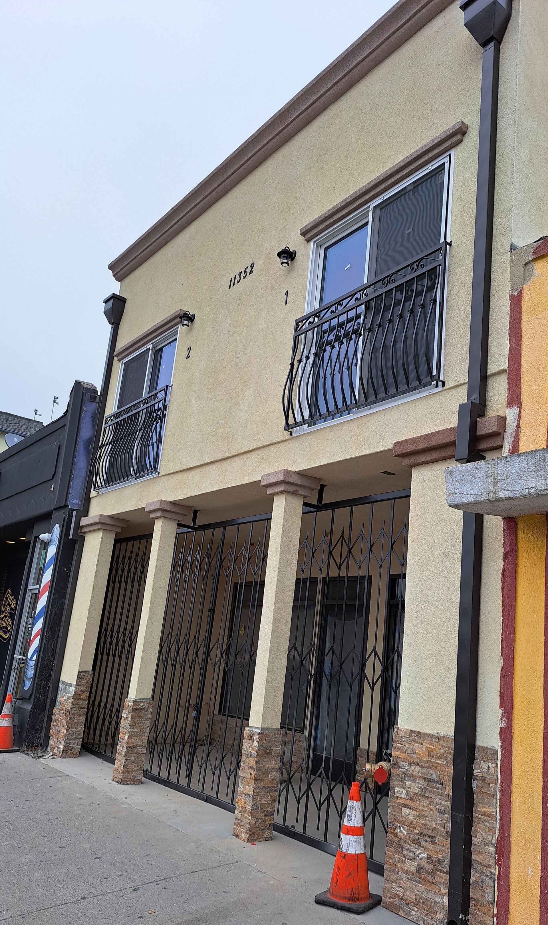 A building with a balcony and a barber shop in the background.