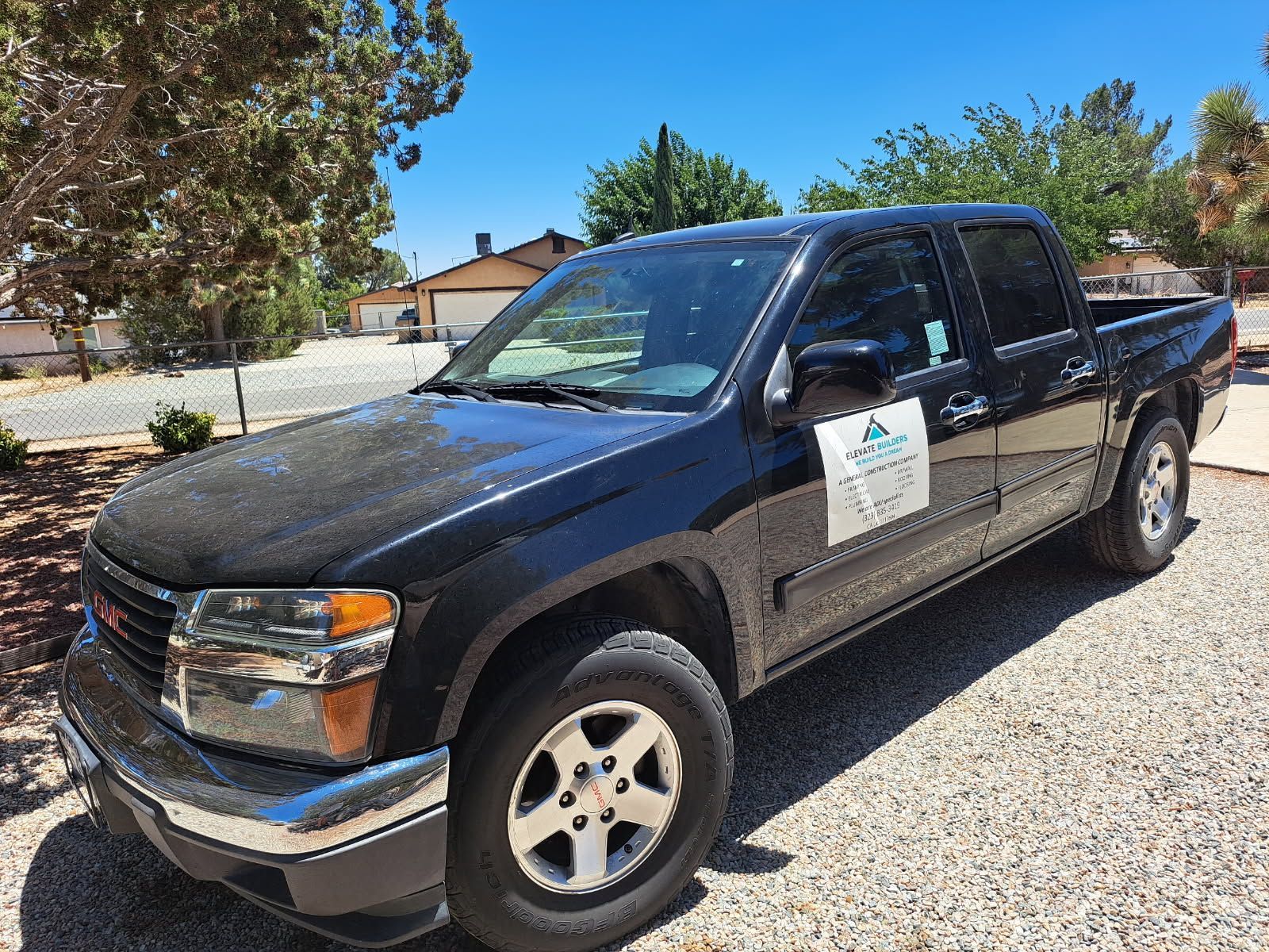 A black pickup truck is parked in a gravel lot.