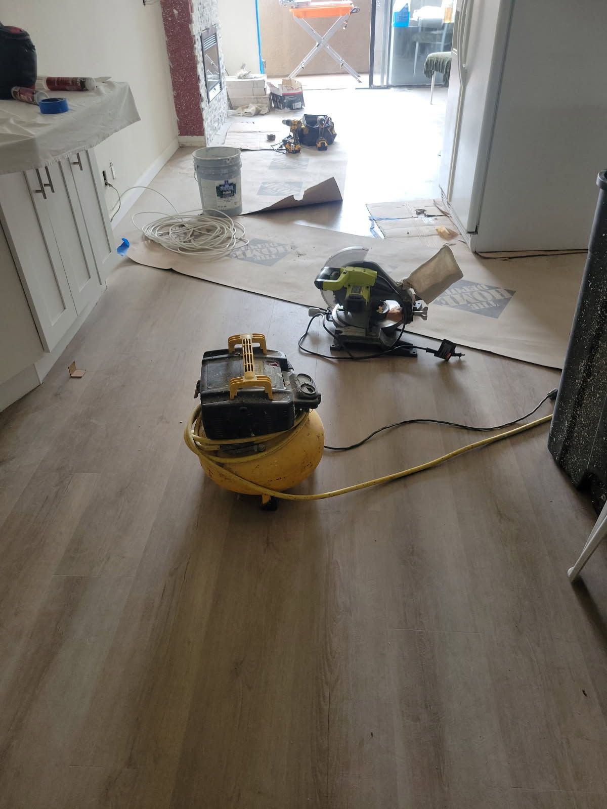 A vacuum cleaner is sitting on the floor next to a circular saw.