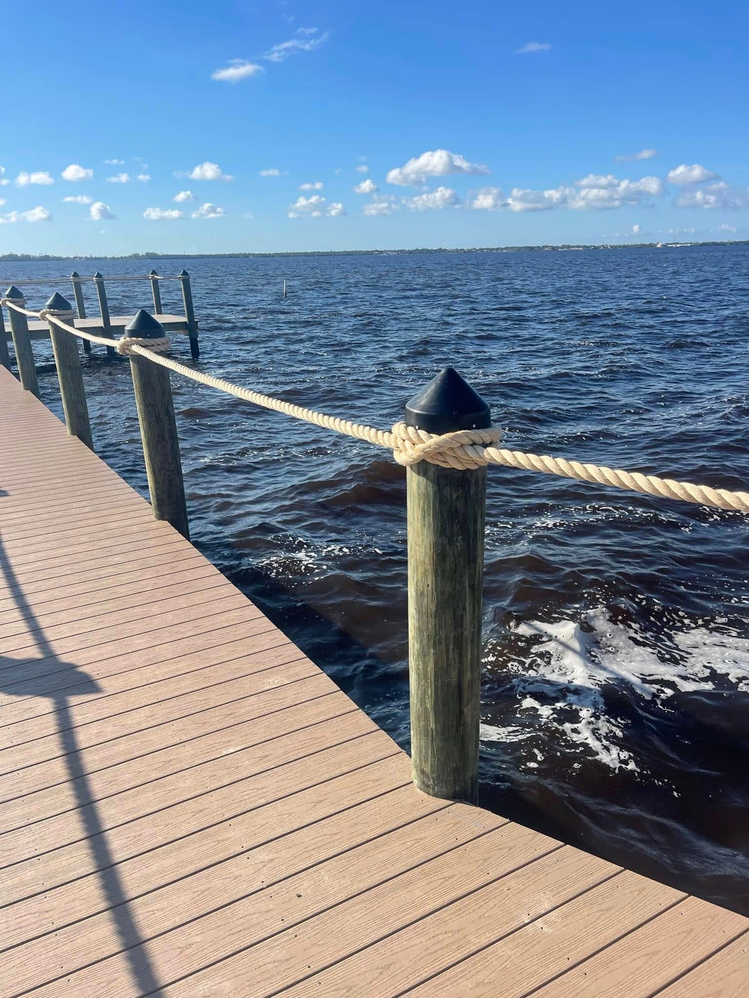 Wooden pier beside choppy blue water under a bright sky with scattered clouds