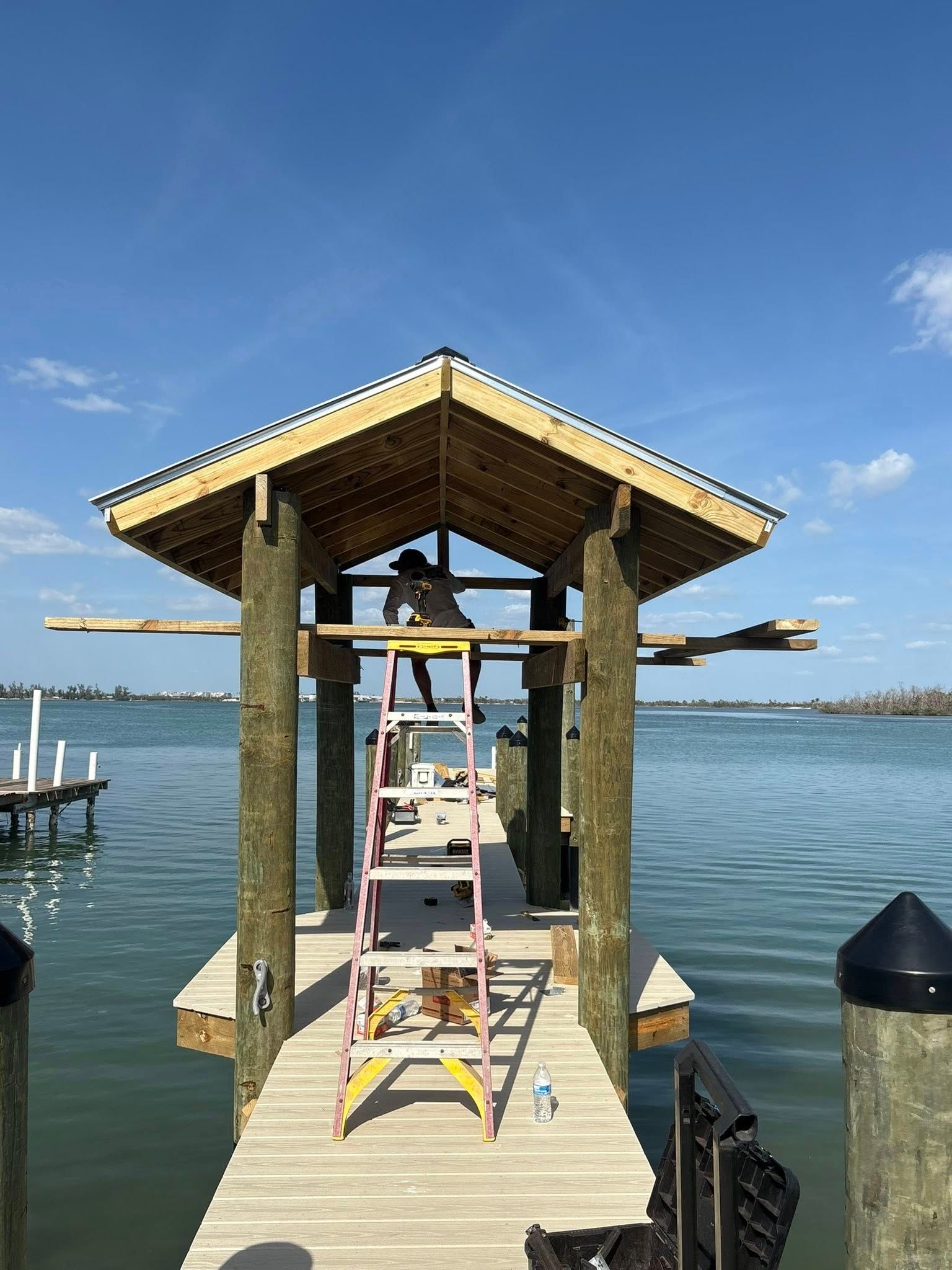 Dock with covered boat lift over calm blue water under a clear sky
