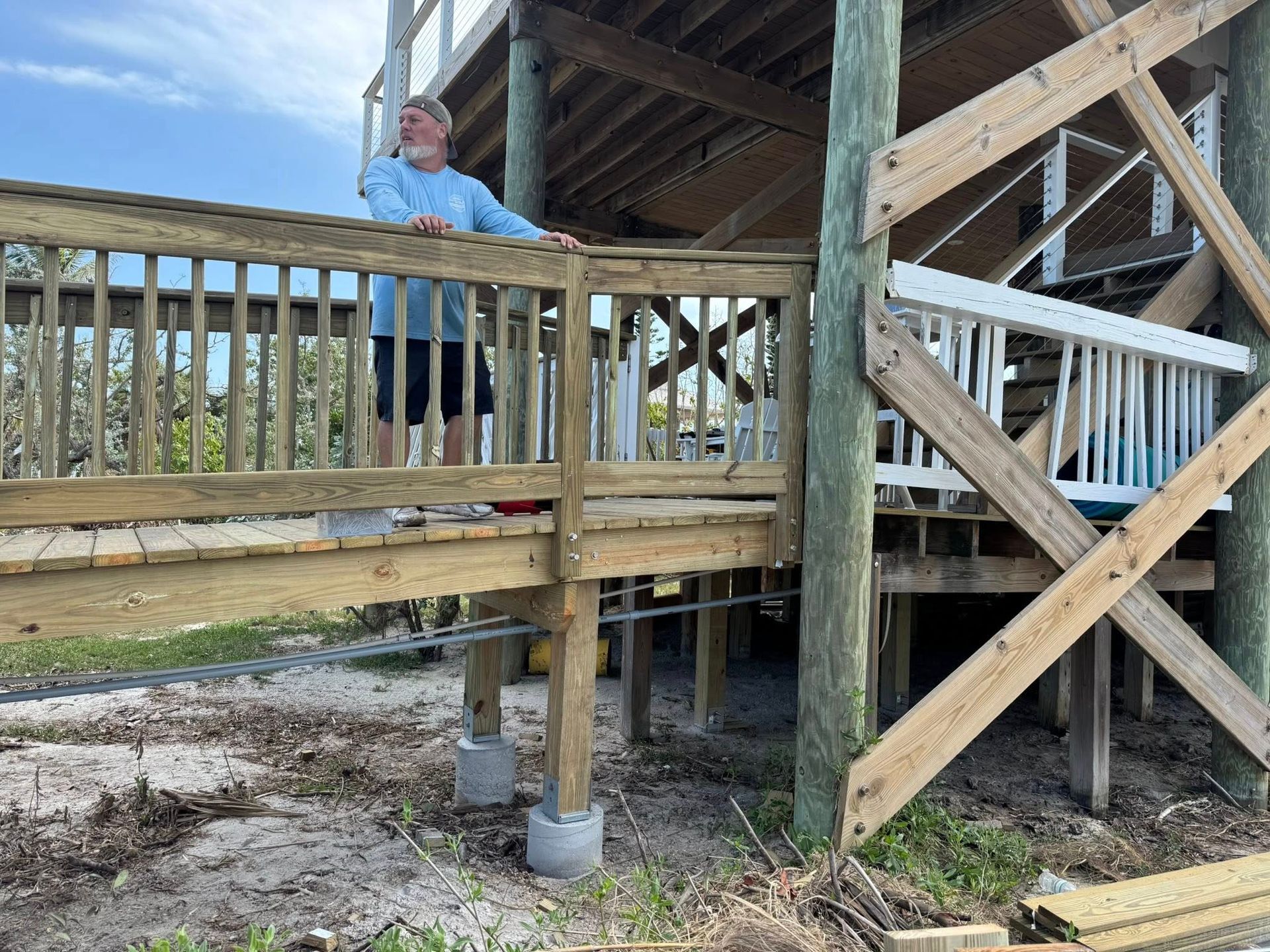 Person on a wooden deck under construction, beside stairs and support beams.