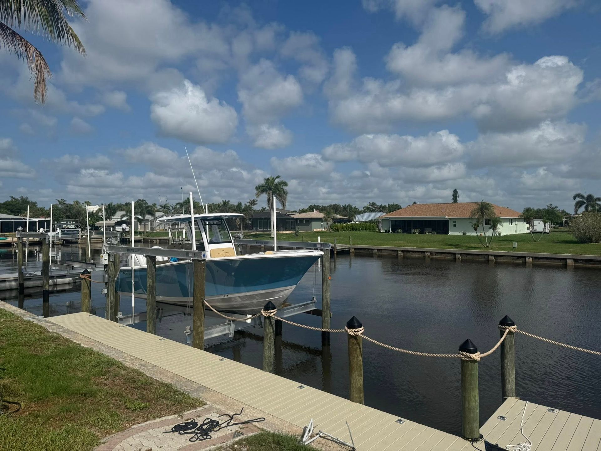 Marina with docked boats, calm water, and a cloudy blue sky over a waterfront neighborhood