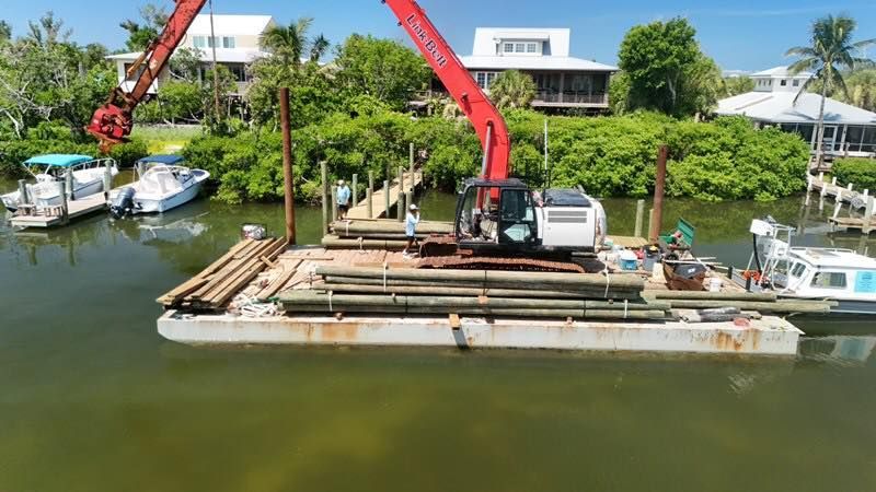 Red crane on a floating barge working in a canal beside waterfront houses and lush greenery