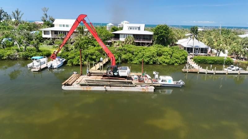 Red crane barge on a canal beside waterfront homes and palm trees