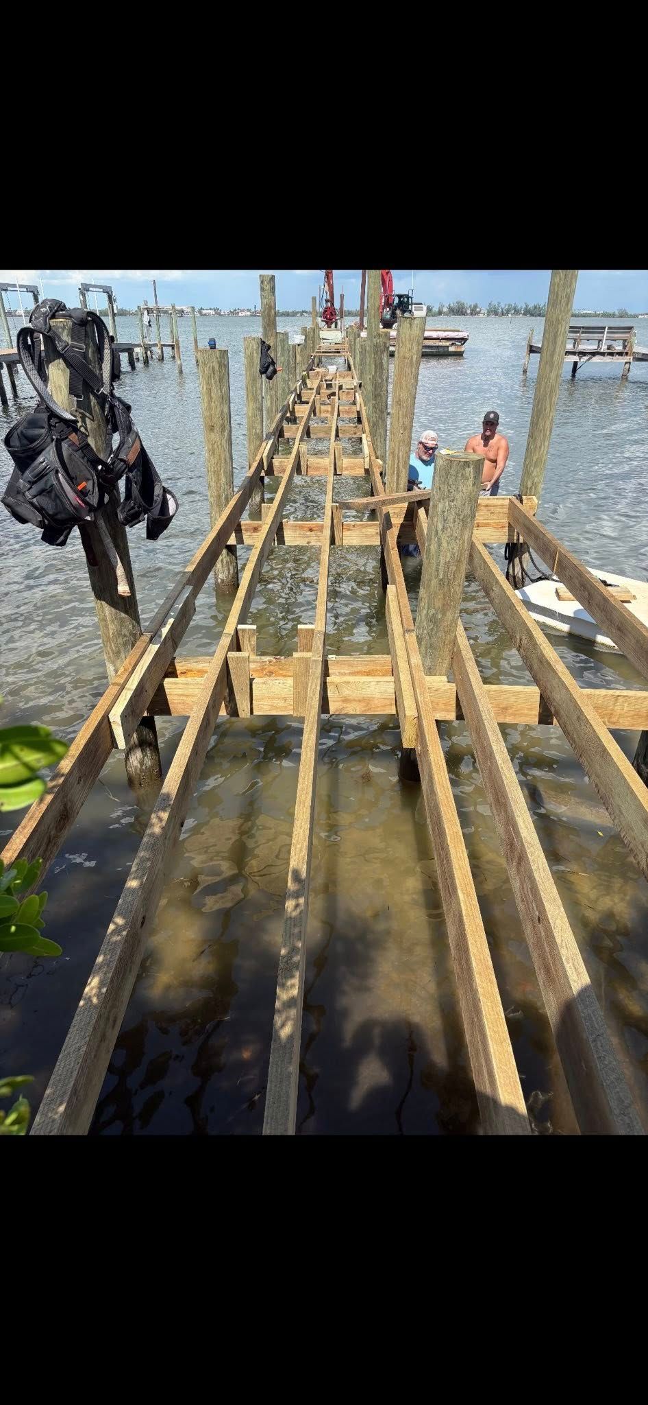 Three people on a wooden dock by the water, with a metal stair structure in the foreground.