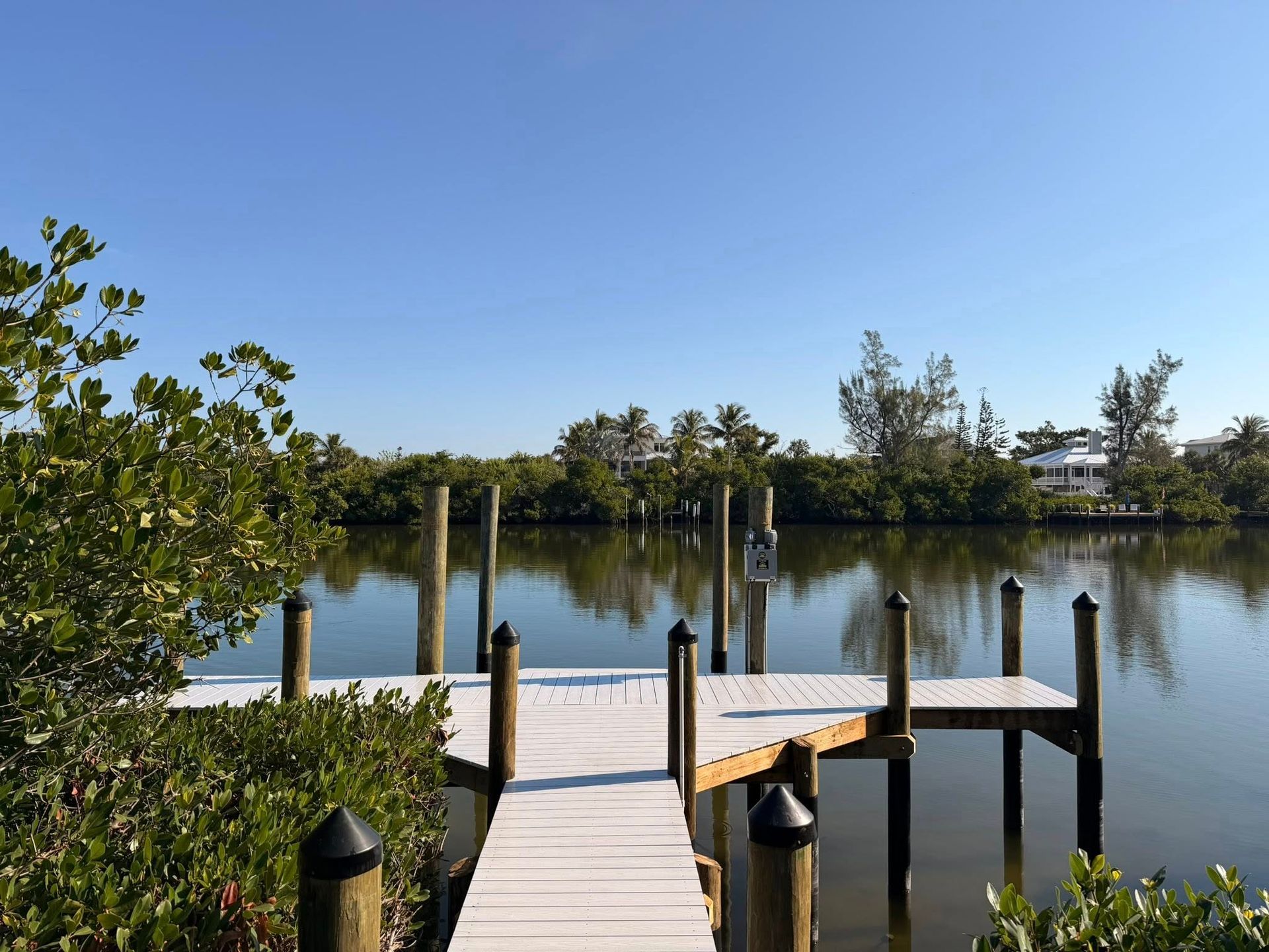 Wooden dock extending into a calm lake with blue sky and trees along the shore