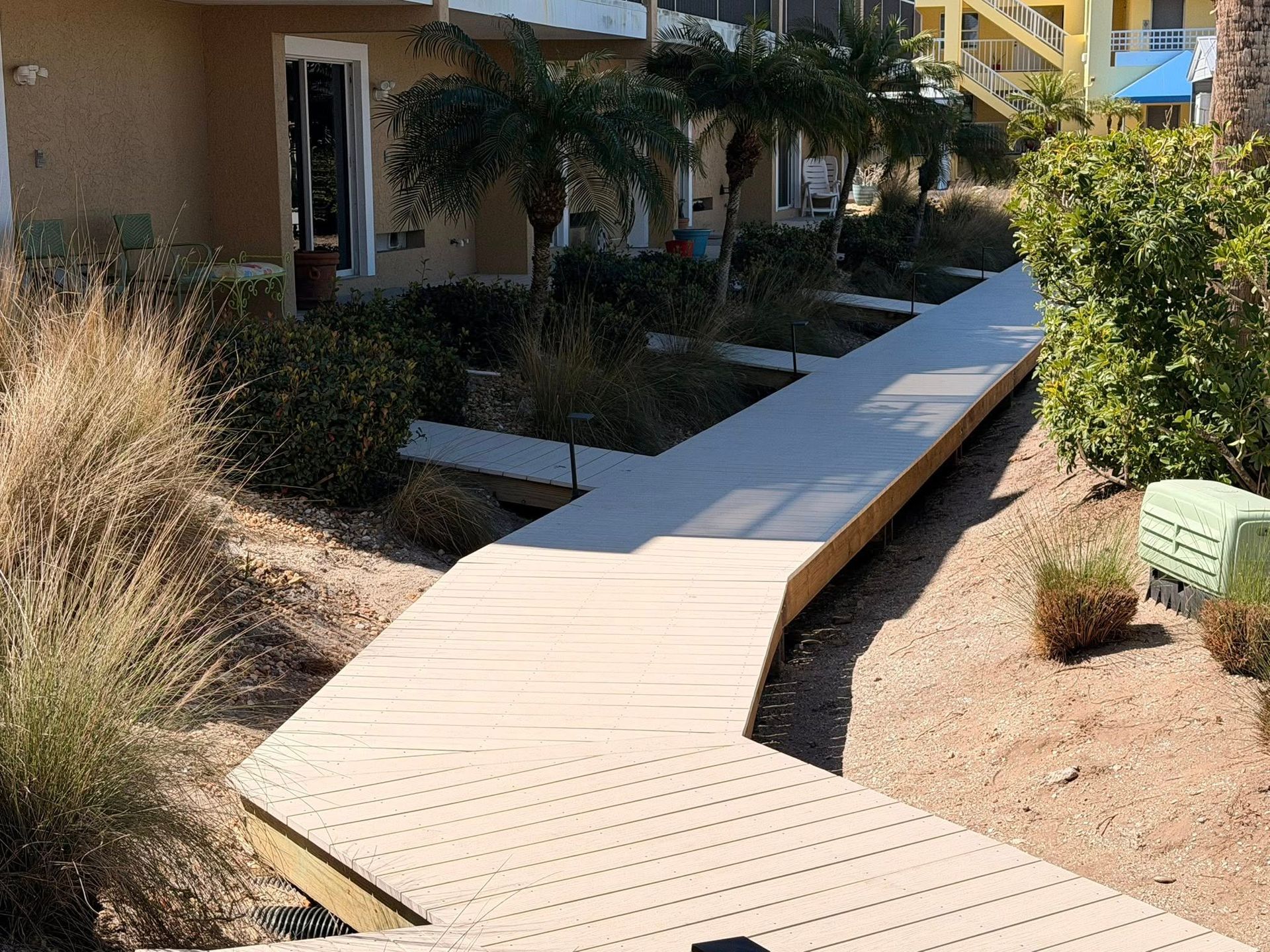 Wooden accessible walkway with railings leading through desert landscaping beside a building