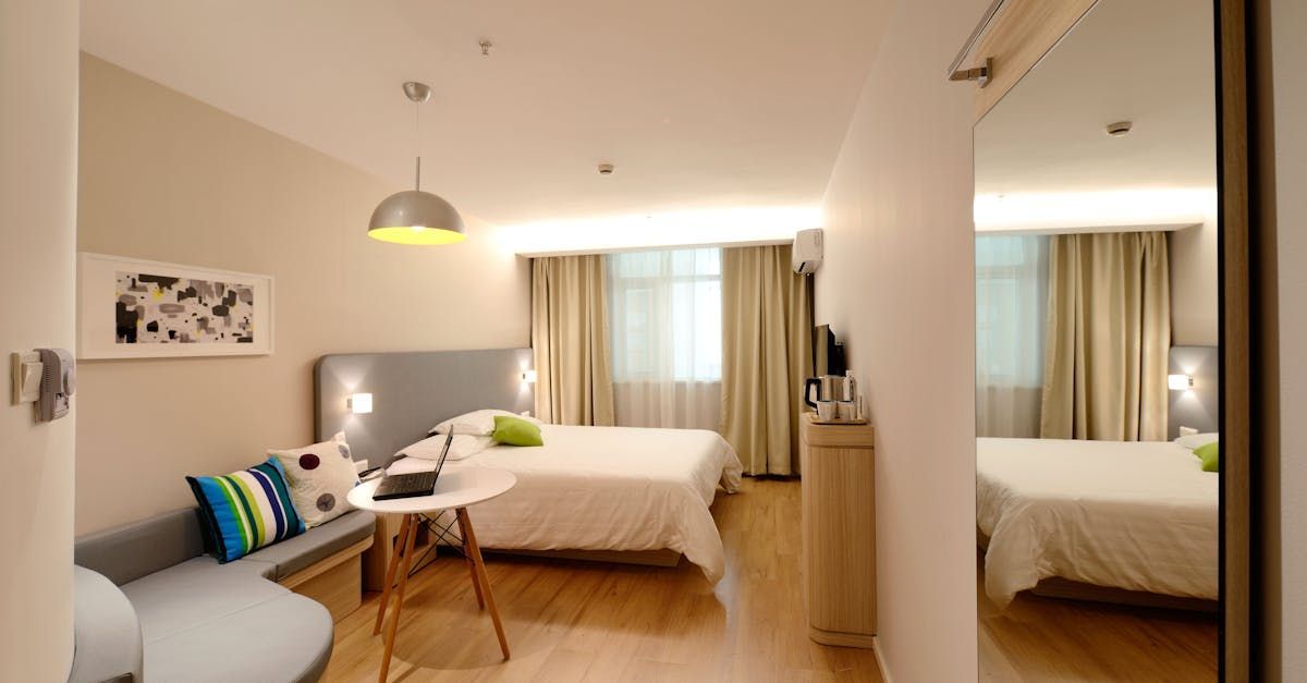 Une chambre d'hôtel avec deux lits, un canapé, une table et un miroir.