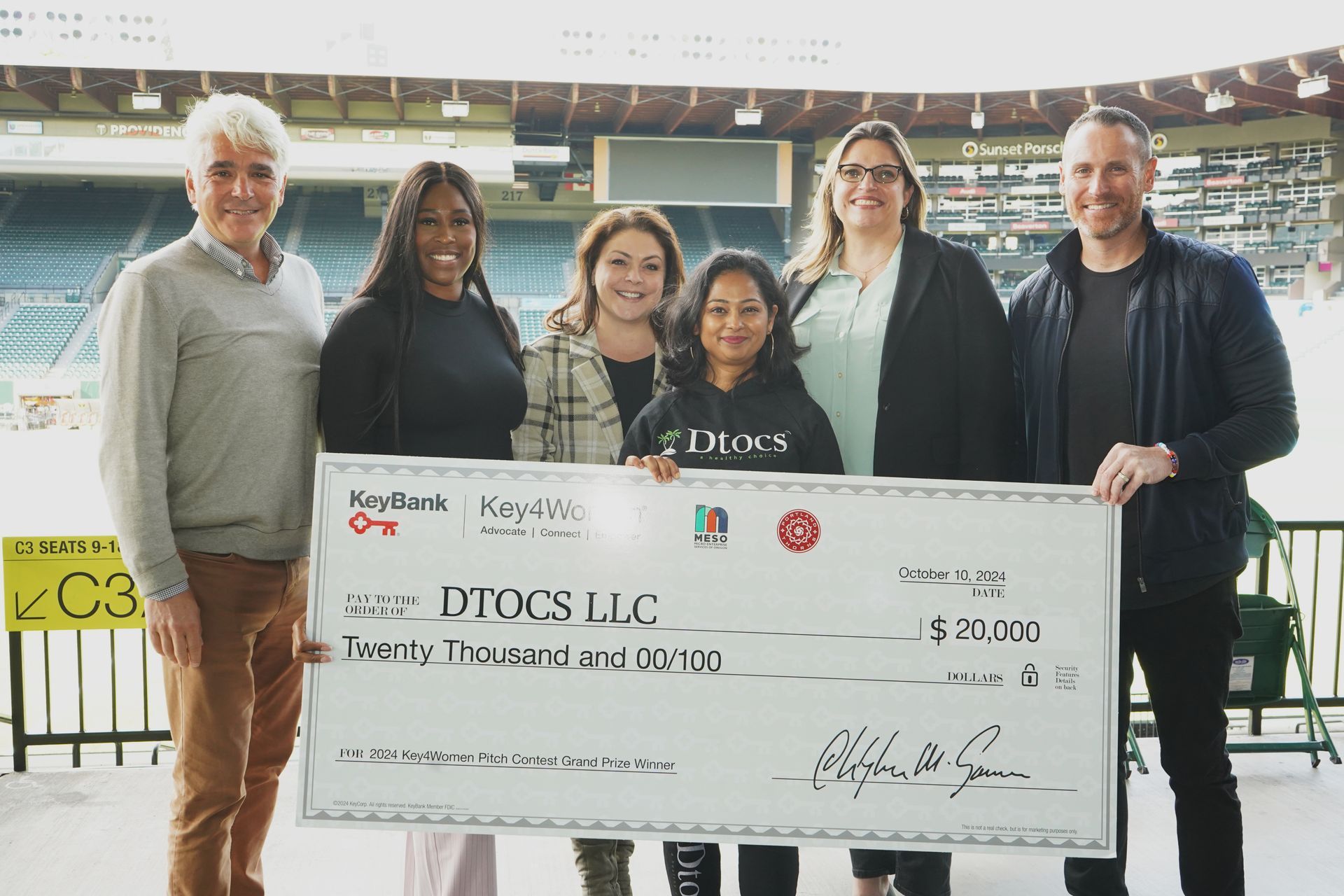 A group of people holding a large check that says dtccs llc