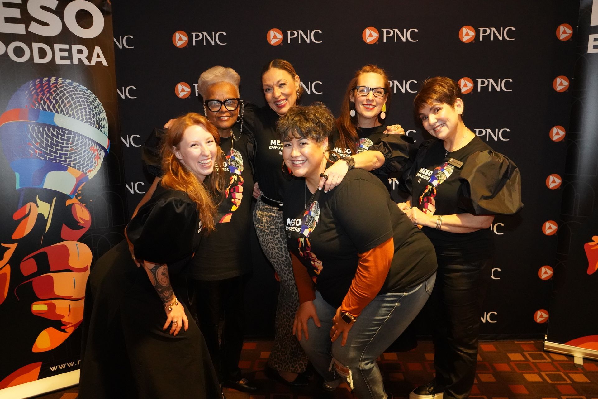 A group of women are posing for a picture in front of a sign that says eso podera.