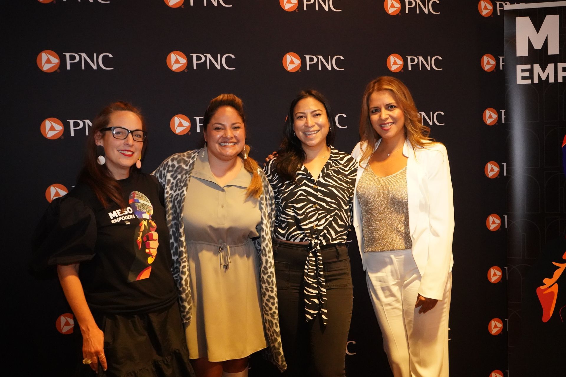 A group of women are posing for a picture in front of a black wall.