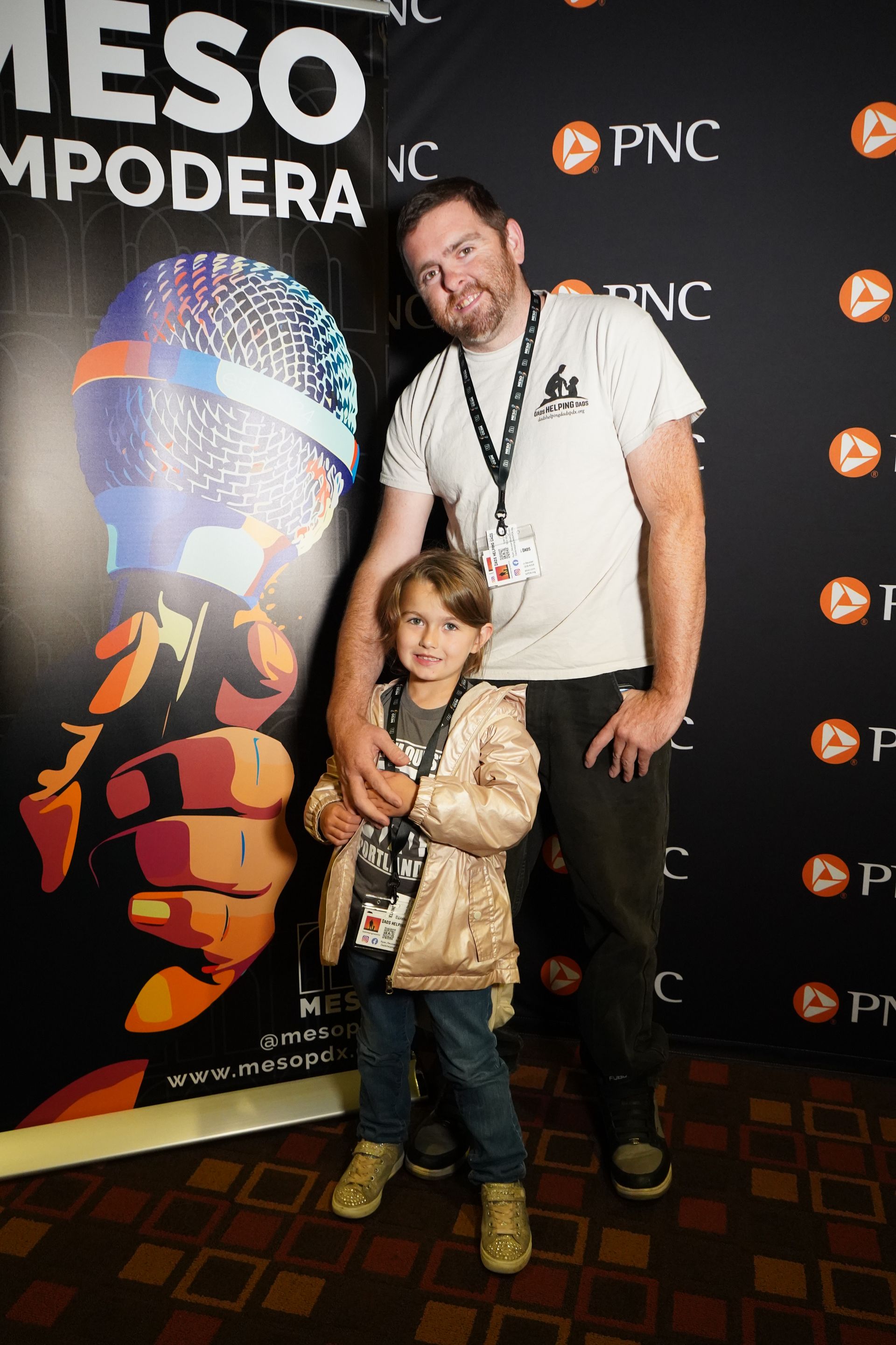 A man and a little girl are posing for a picture in front of a sign.