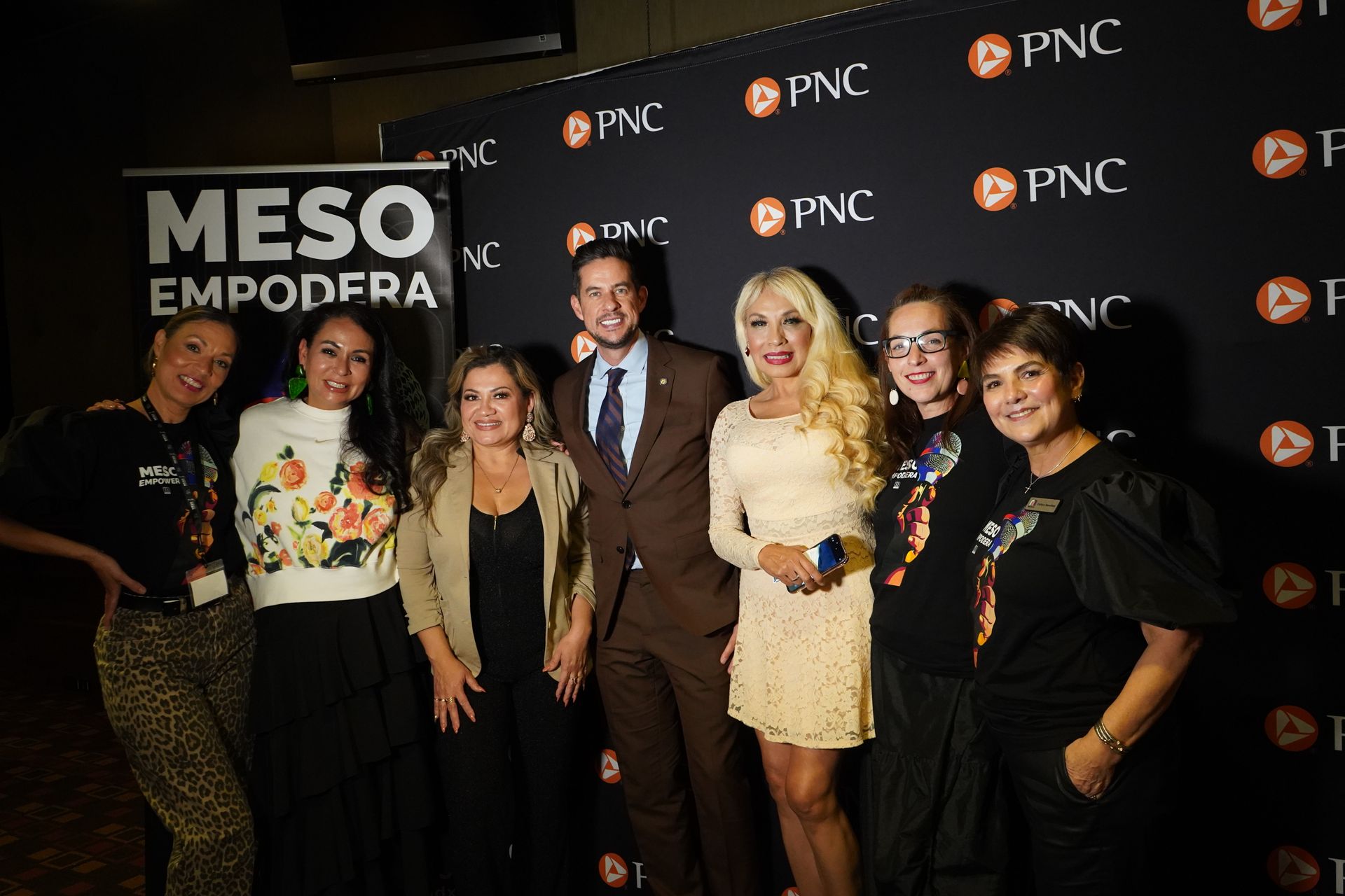 A group of people are posing for a picture in front of a banner that says meso empodera.