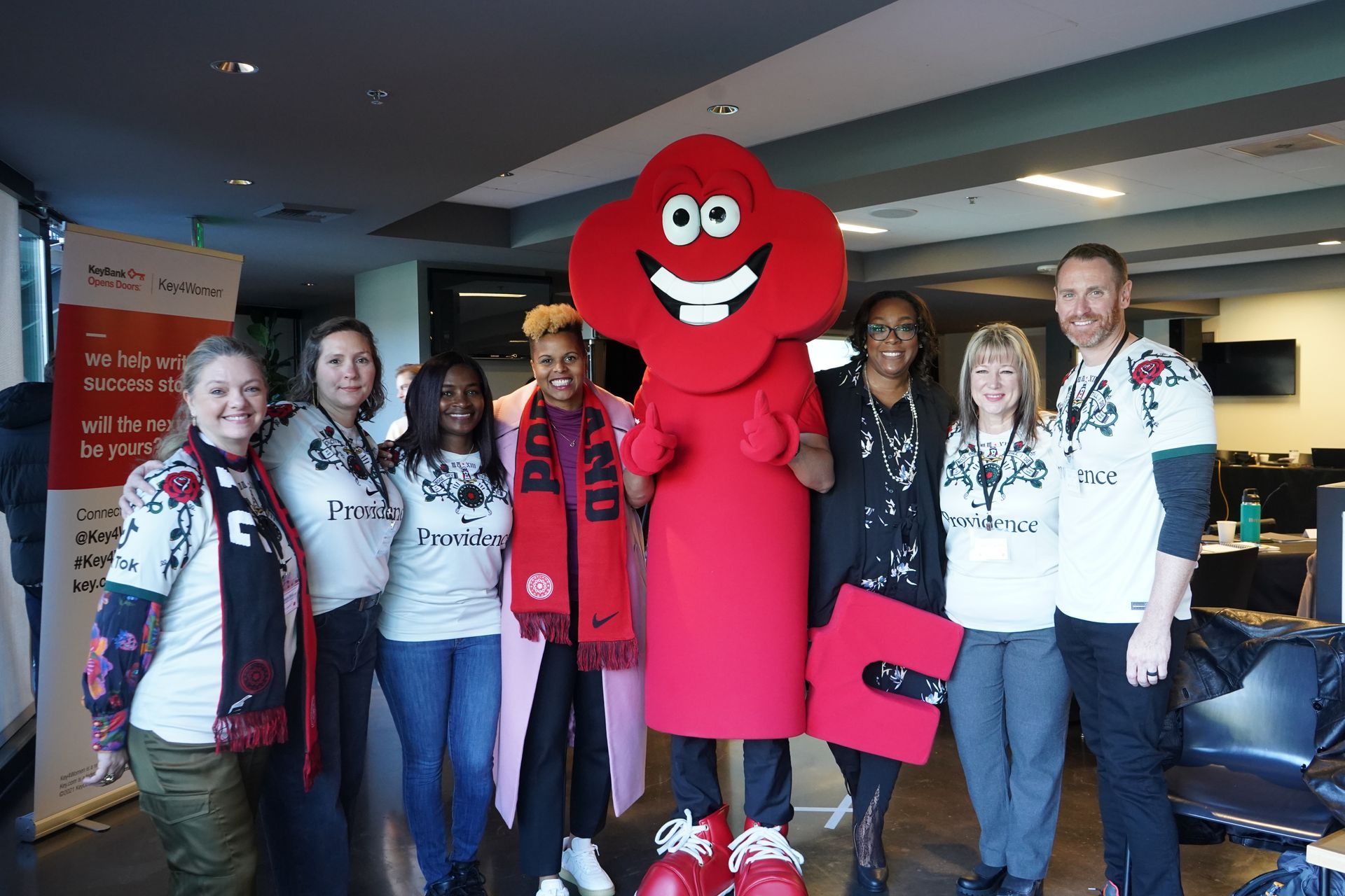 A group of people are posing for a picture with a red mascot.