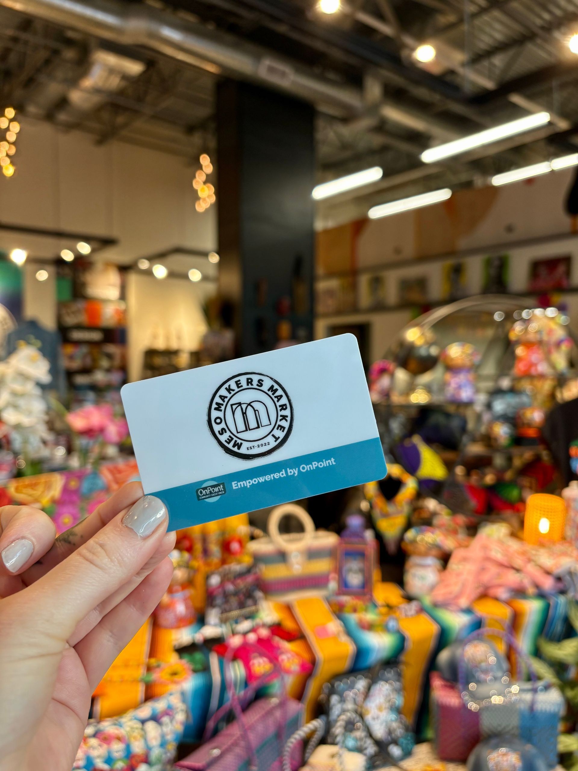 A person is holding a gift card in front of a store full of gifts.