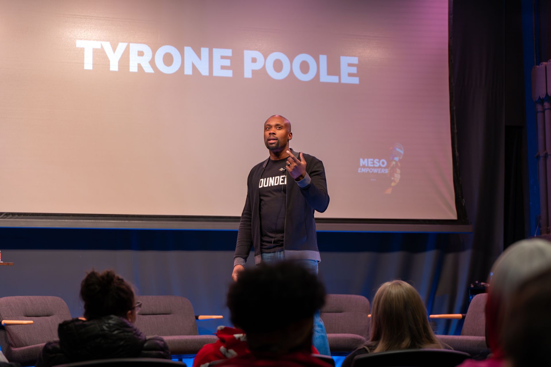 A man is giving a speech in front of a crowd in a theater.