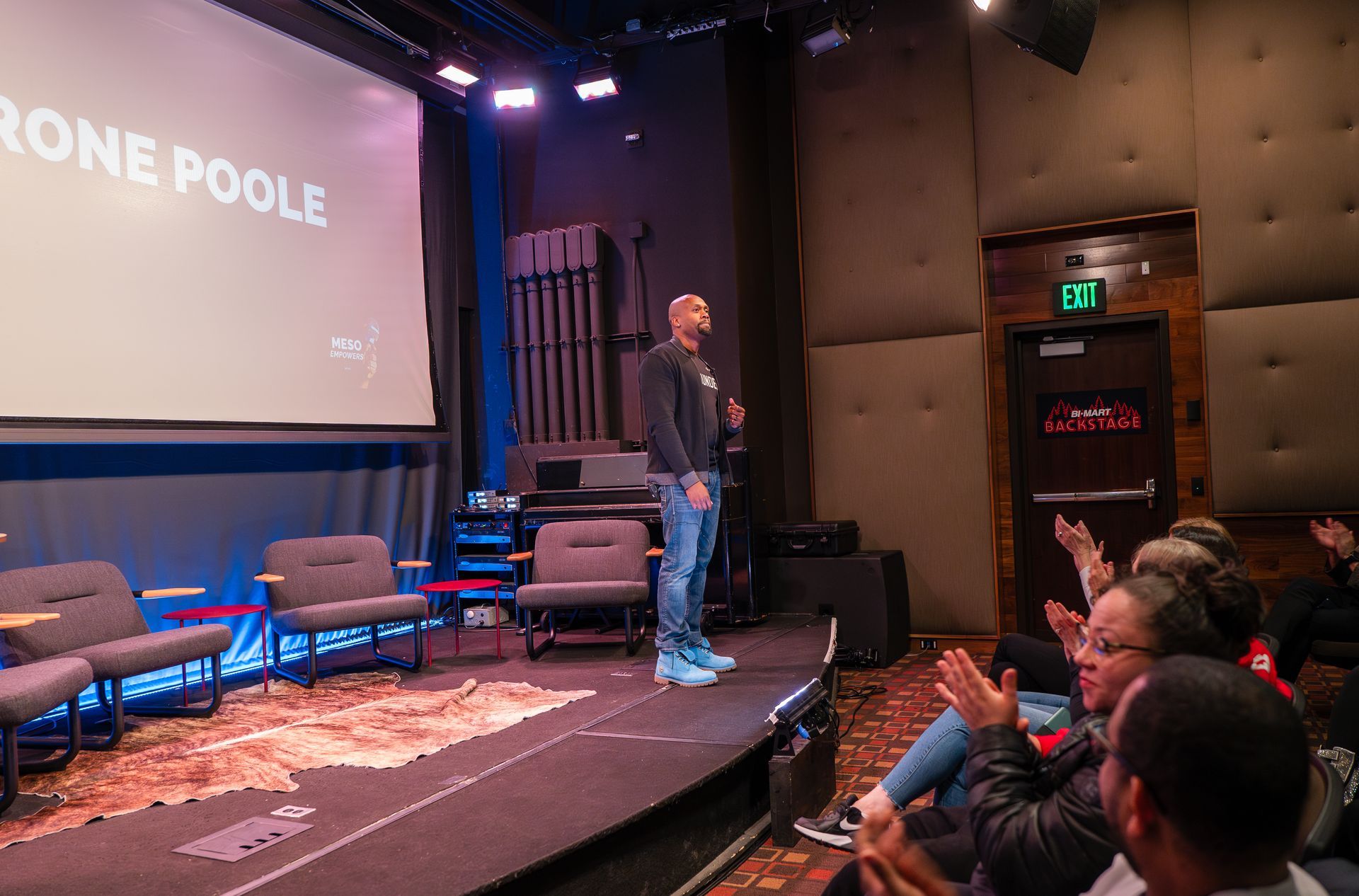 A man is standing on a stage giving a presentation to a group of people.