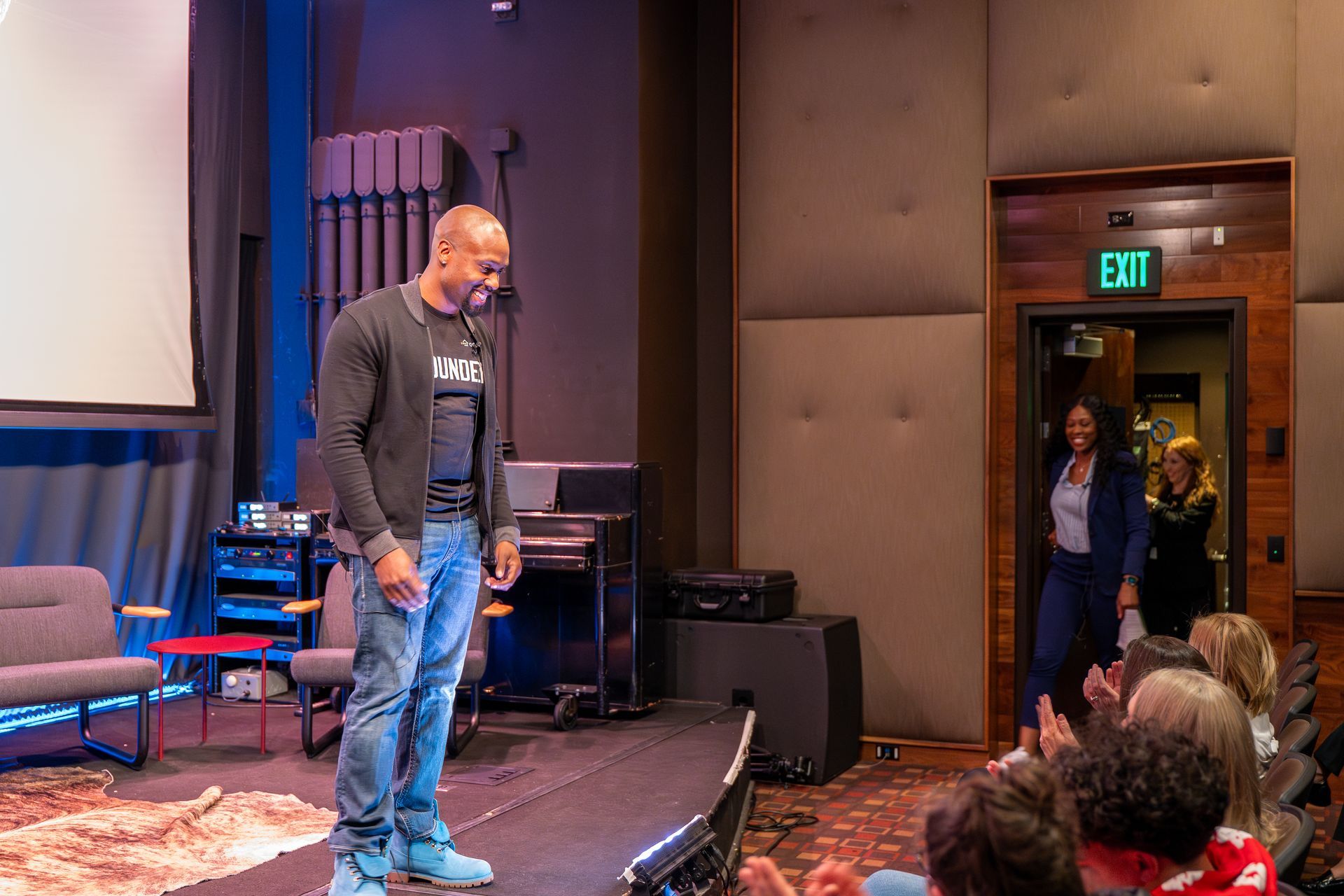 A man is standing on a stage in front of a crowd of people.