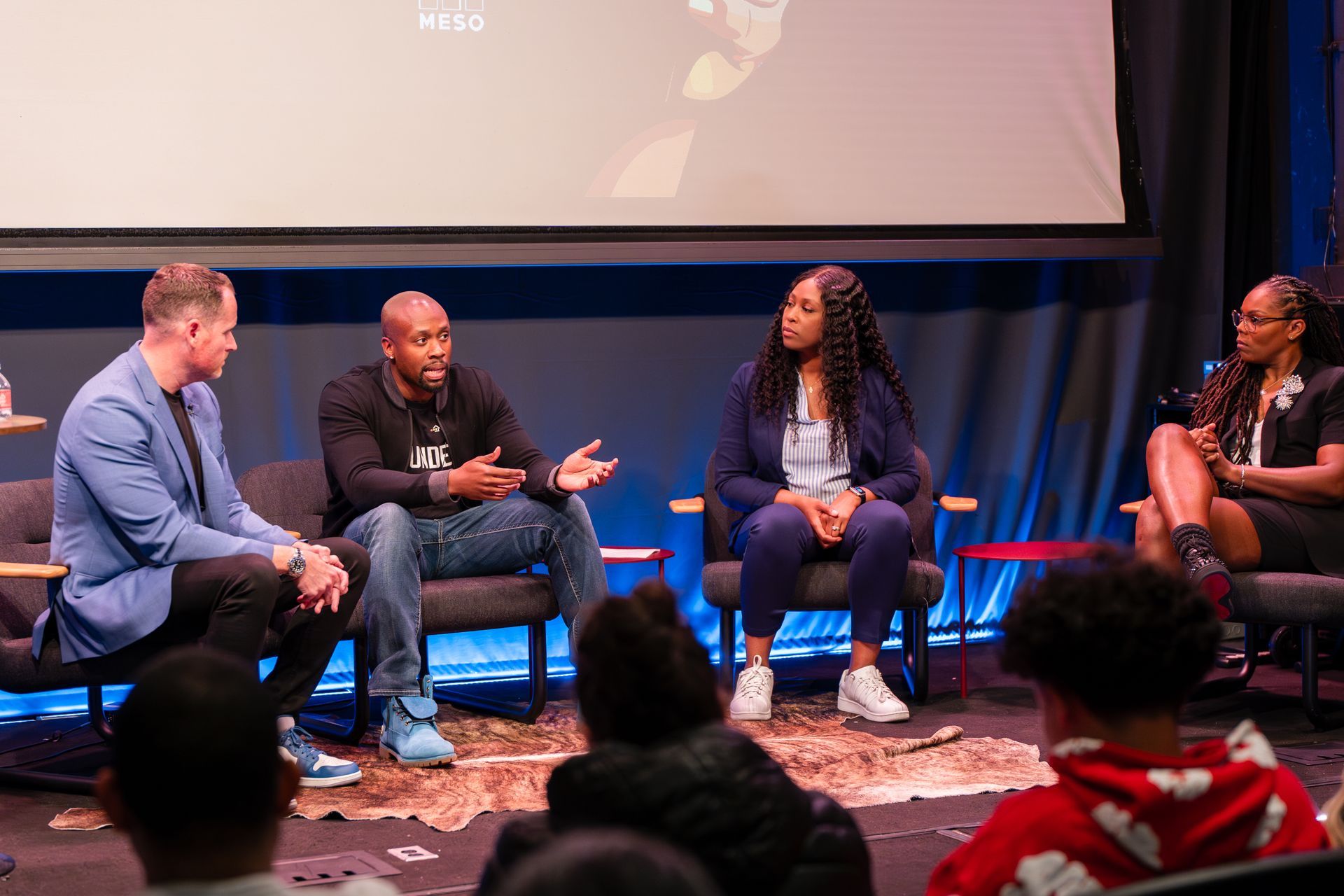 A group of people are sitting on a stage talking to each other.