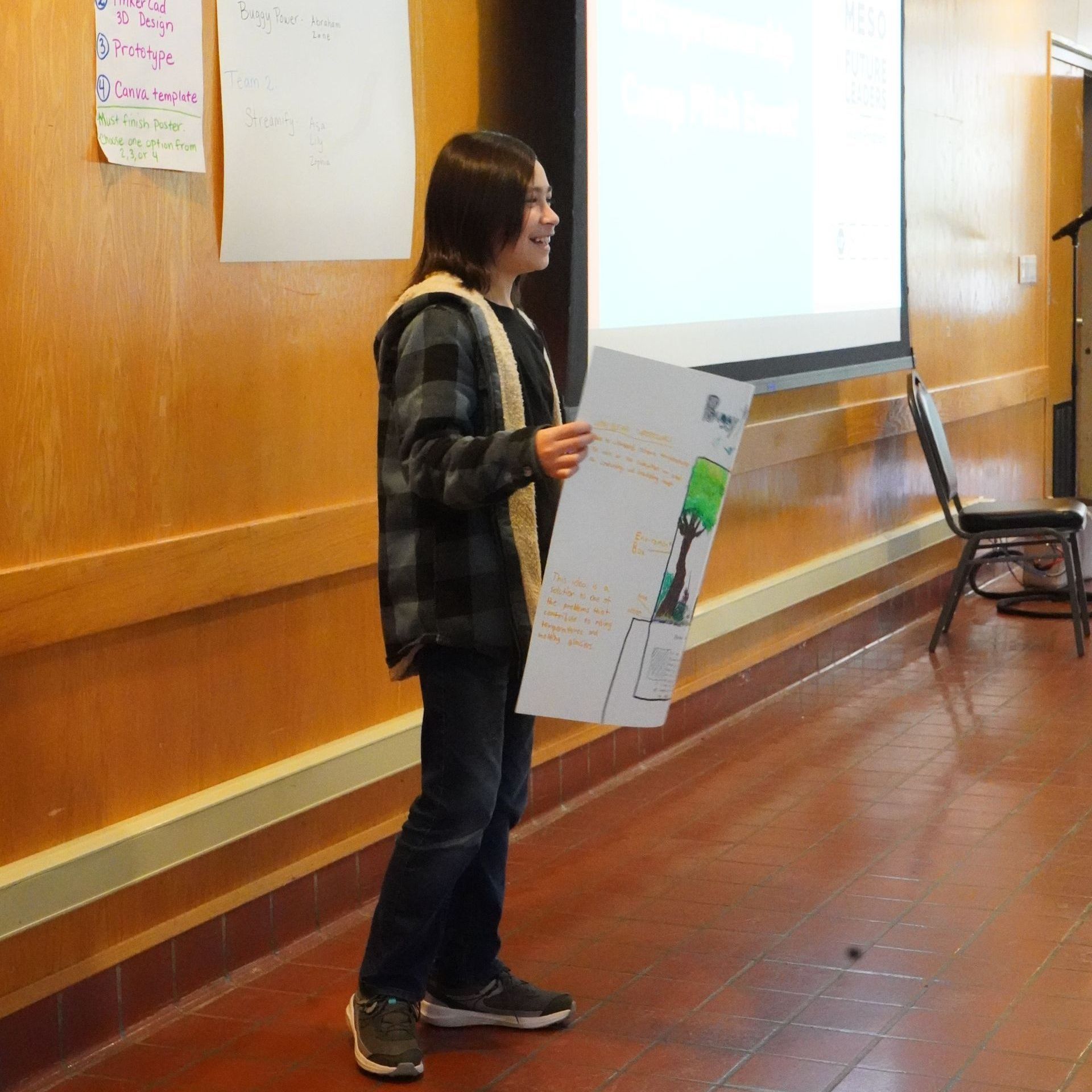 A woman stands in front of a projector screen holding a piece of paper