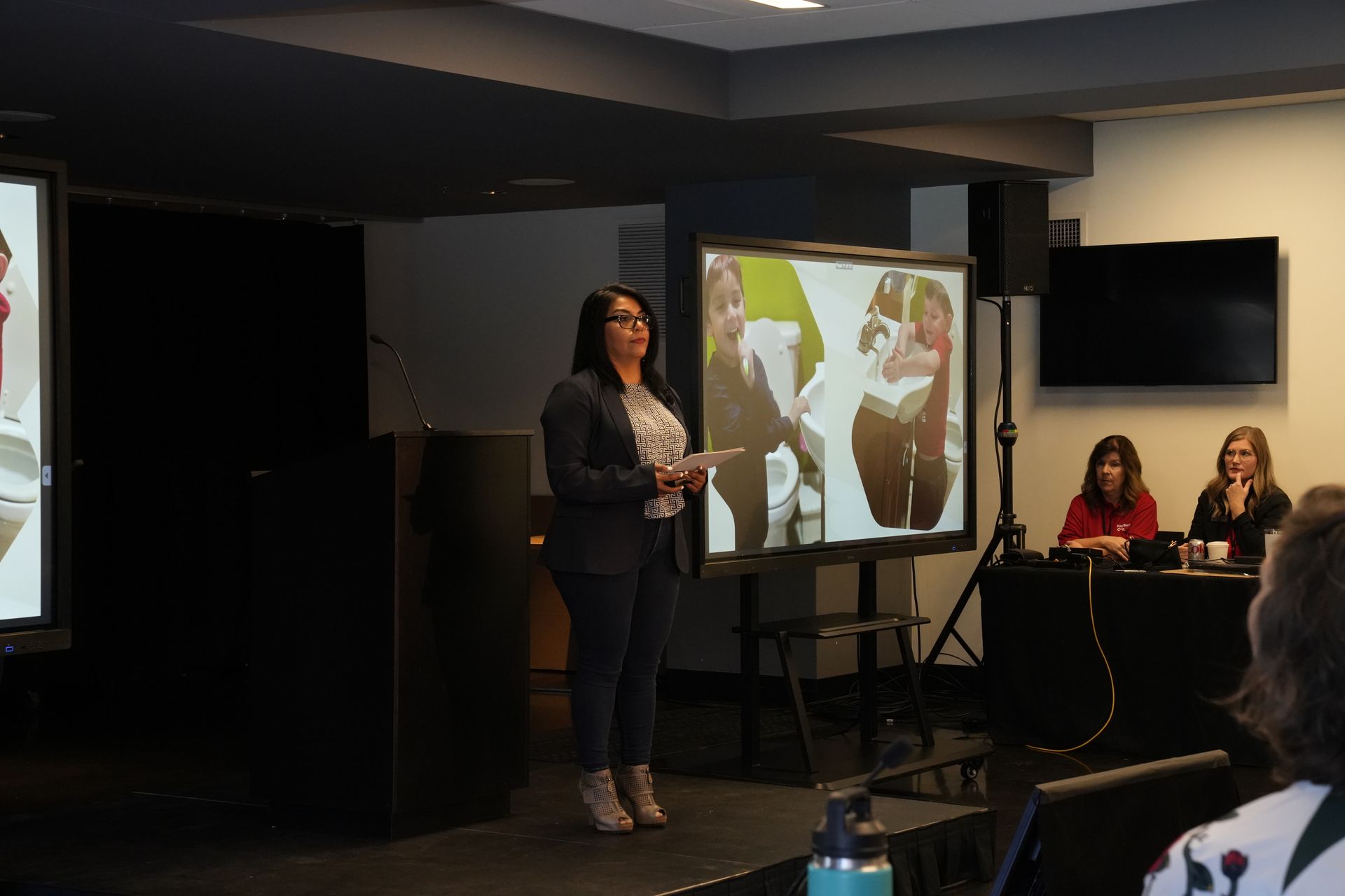 A woman is giving a presentation in front of a group of people.
