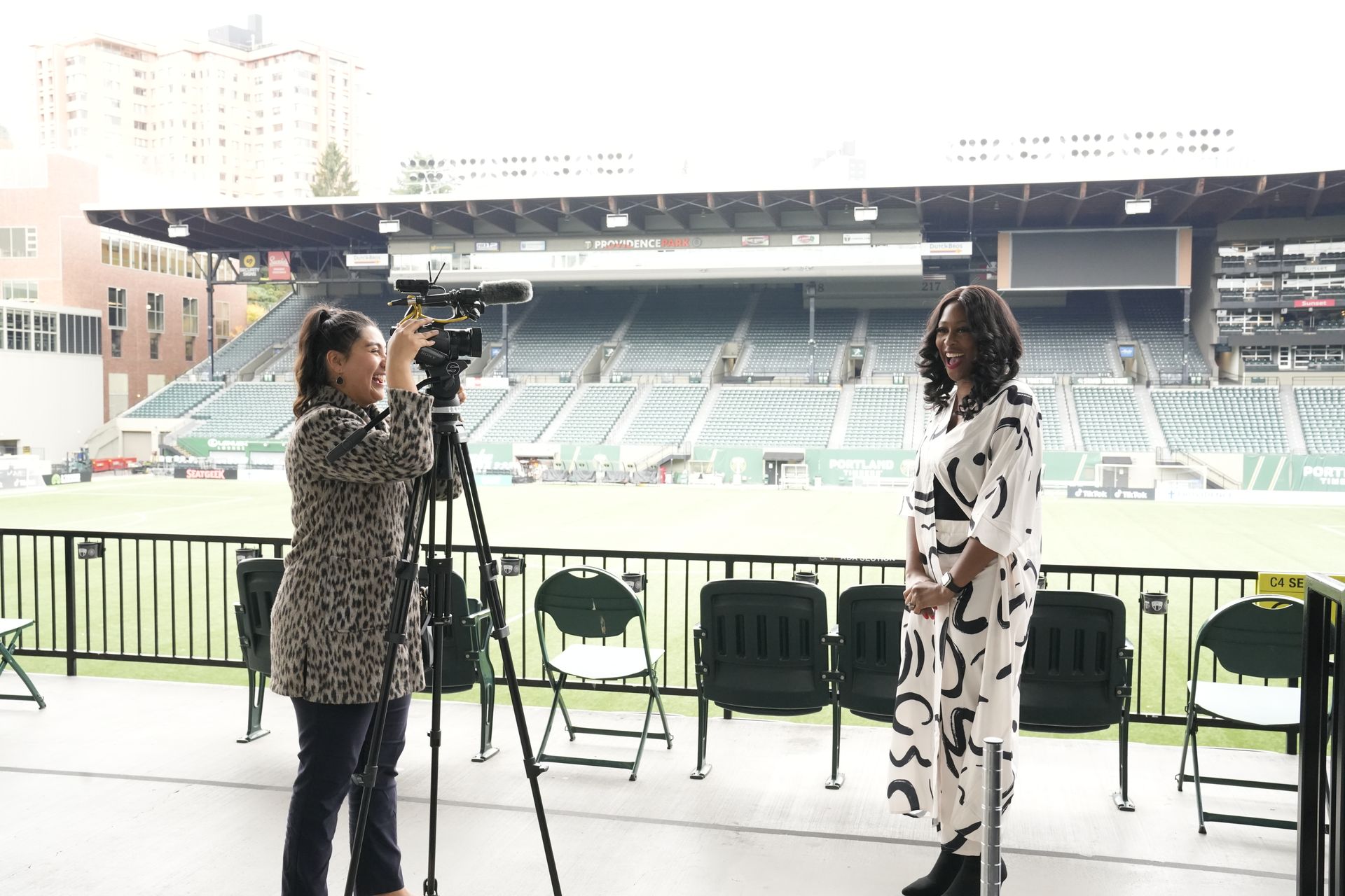 A woman is standing in front of a camera in a stadium.