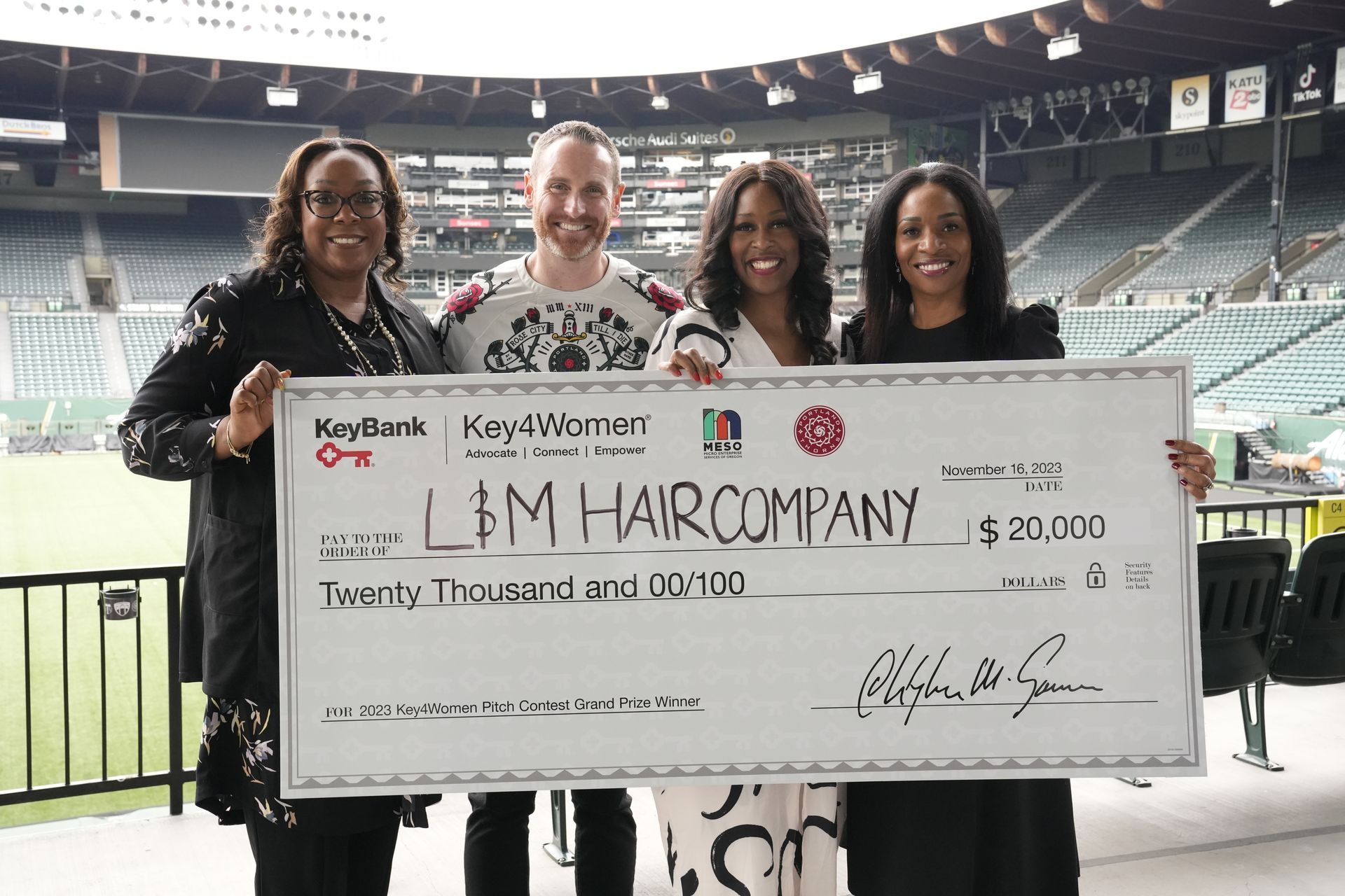 A group of people holding a large check for lem hair company