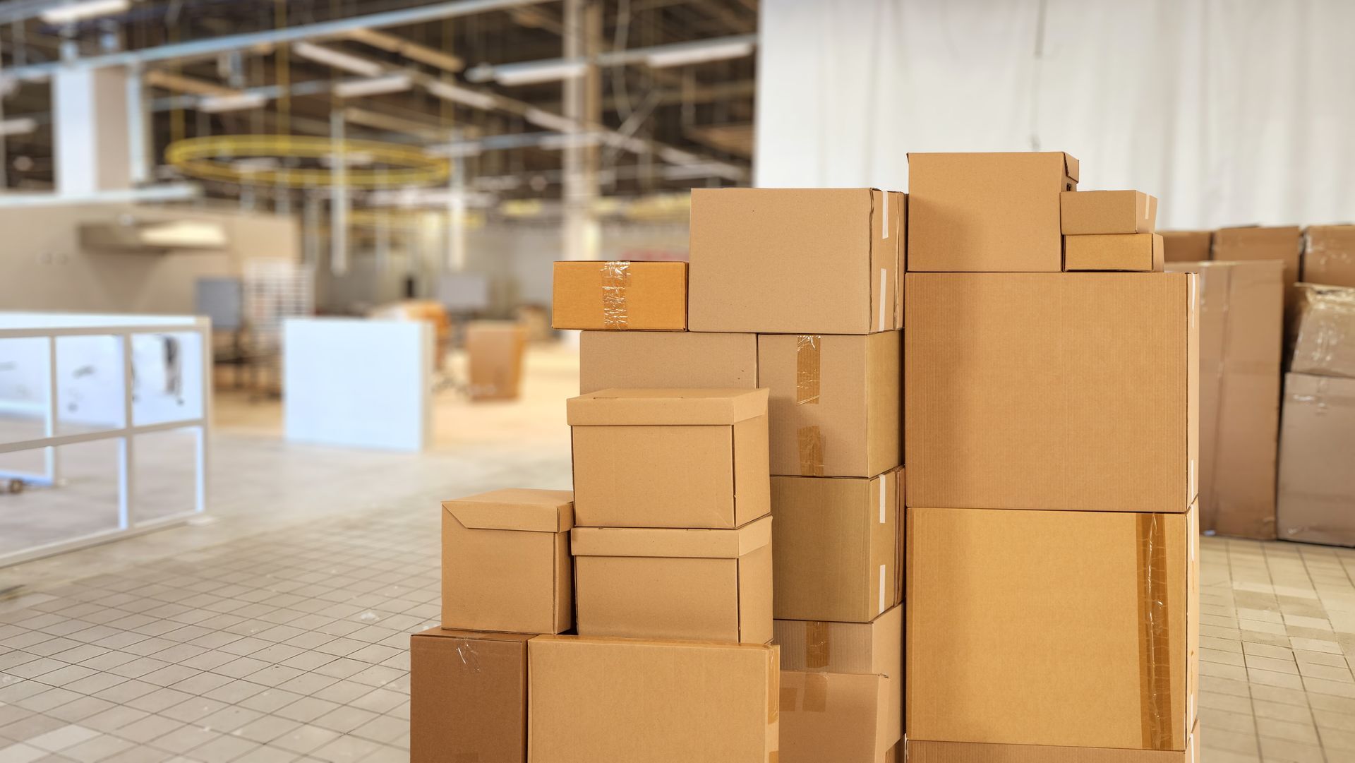 Stacked cardboard boxes in a warehouse or storage area on a tiled floor