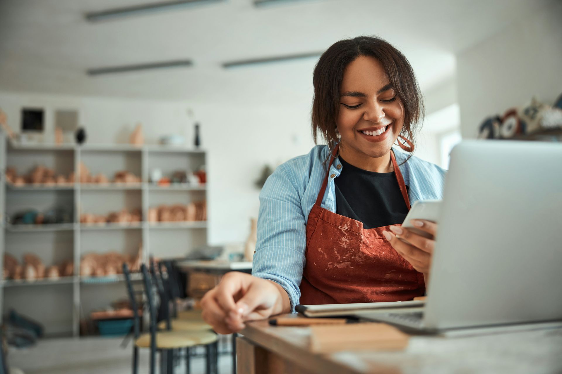 Person smiling and using a laptop while holding a credit card in a cozy café setting