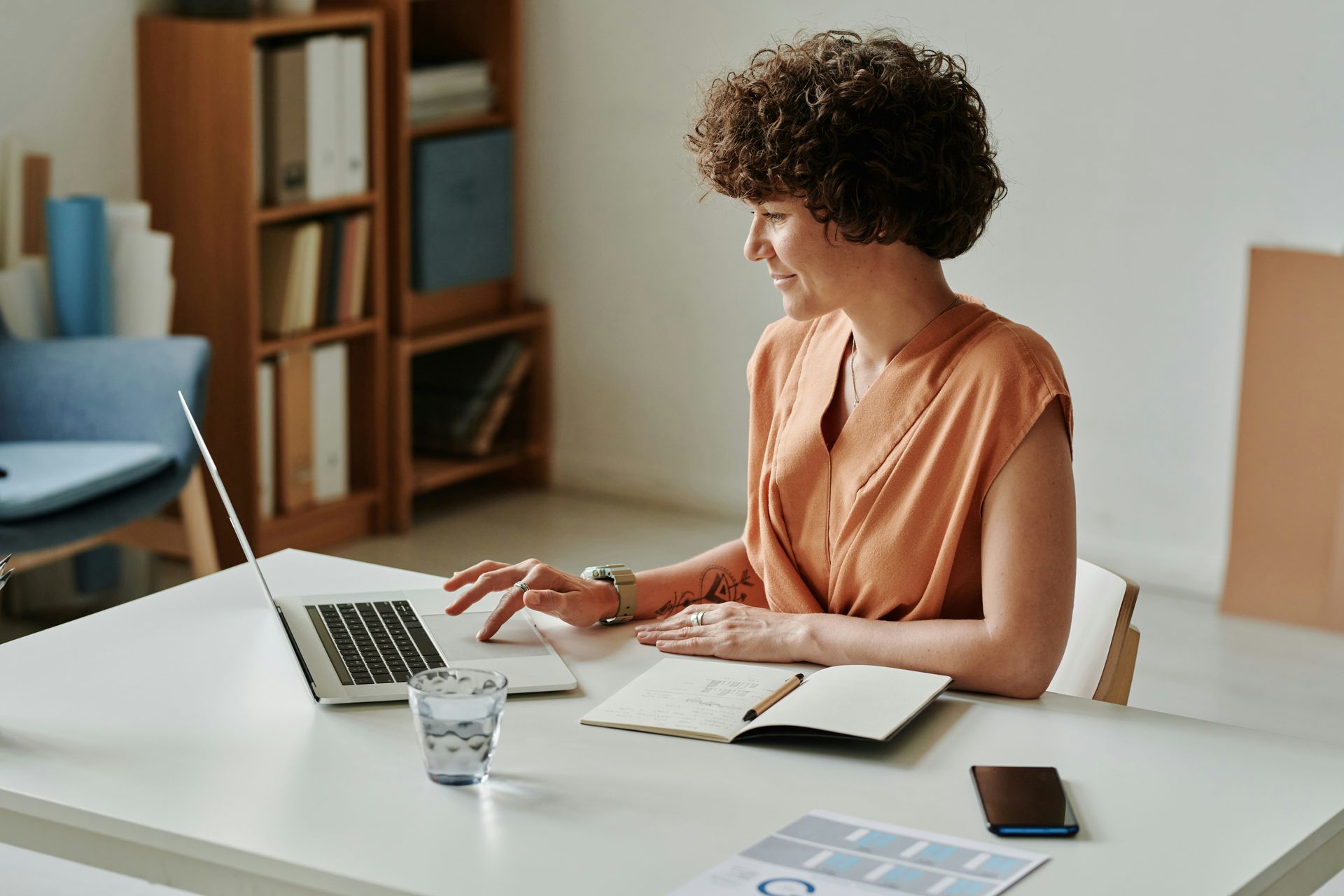 Person working at a laptop and notebook on a desk in a bright room