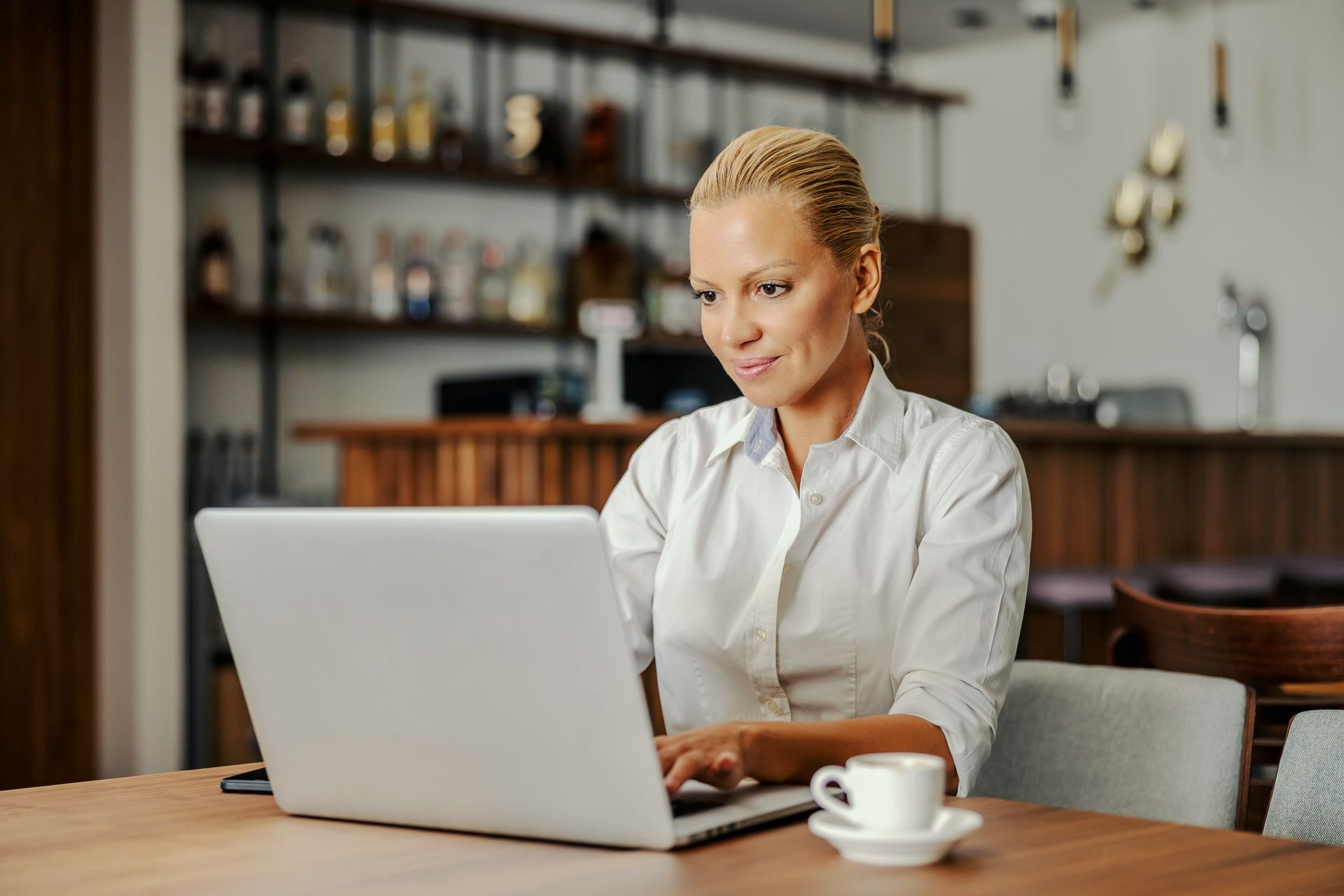 Person working on a laptop at a café table with a cup of coffee