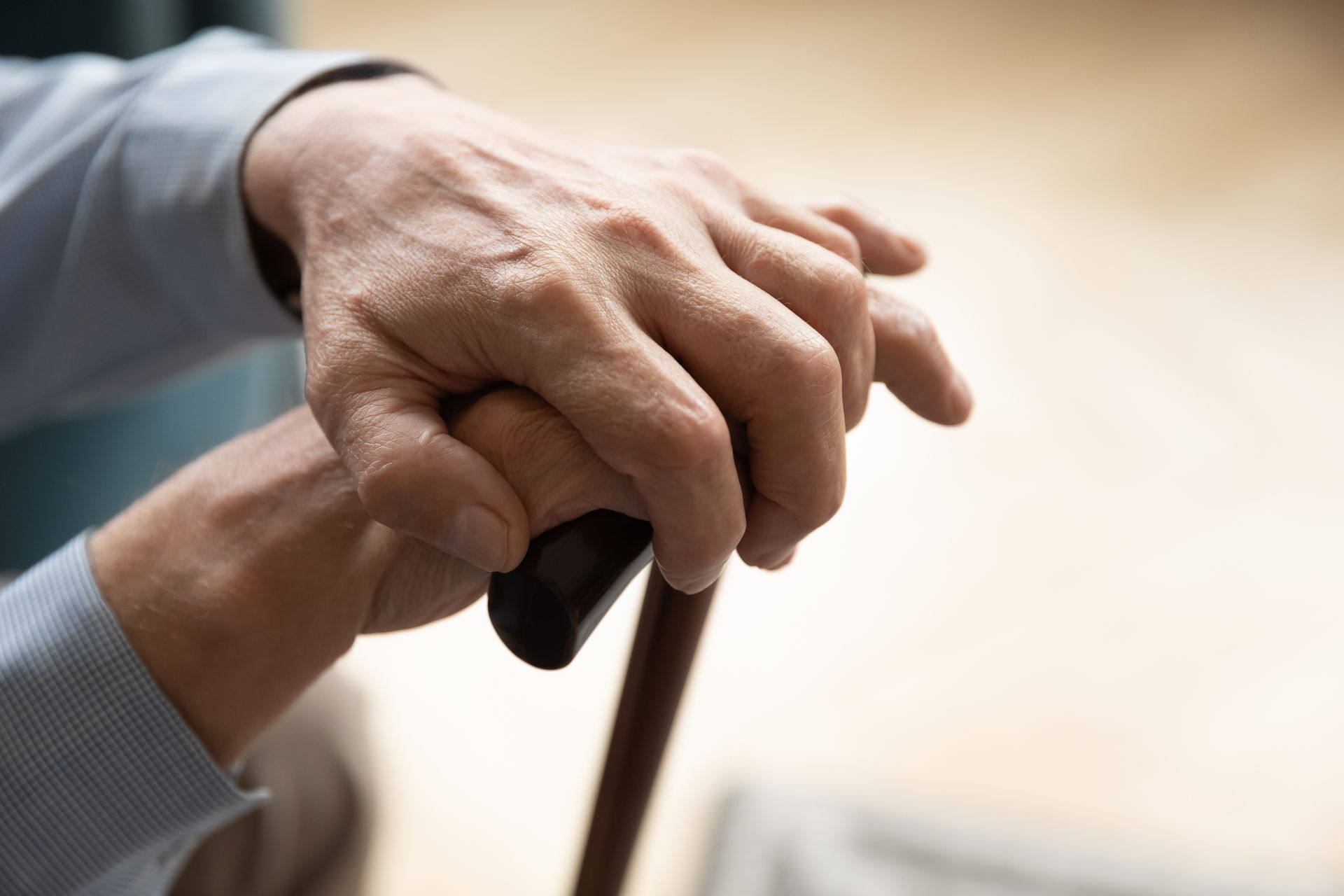 An elderly man is holding a cane in his hand.