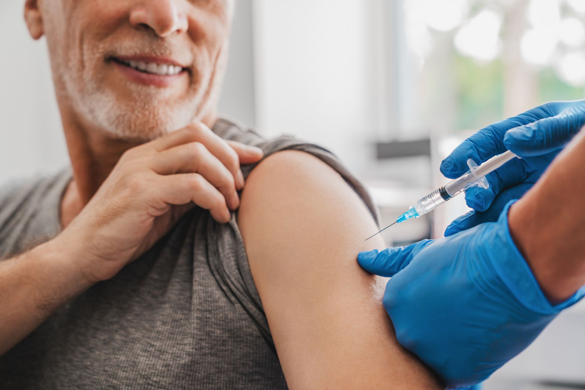 Doctor making injection to senior patient in clinic.