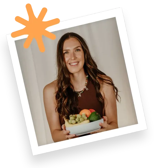 Woman holding a bowl of fresh vegetables and fruit, smiling in a tilted portrait against a light background.